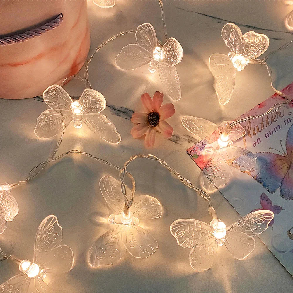 Guirnalda de mariposas transparentes encendida sobre una mesa de mármol rosa