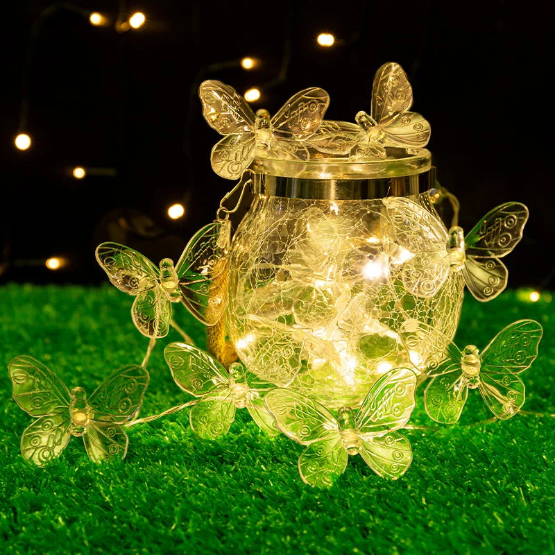 Mariposas verdes rodeando un tarro de cristal con luces, de noche