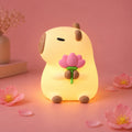 El Capibara Glow encendido con la flor de loto rosa entre las manos