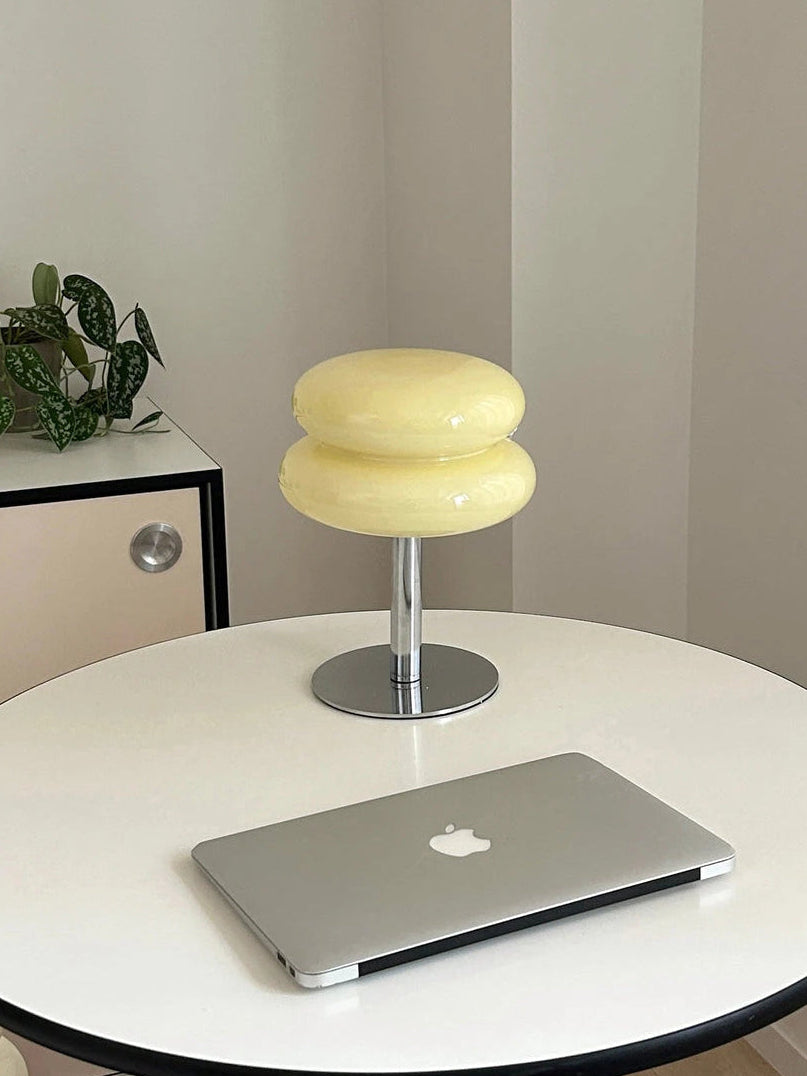 Lumi Cloud beige en una mesa redonda, junto a un portátil y una planta