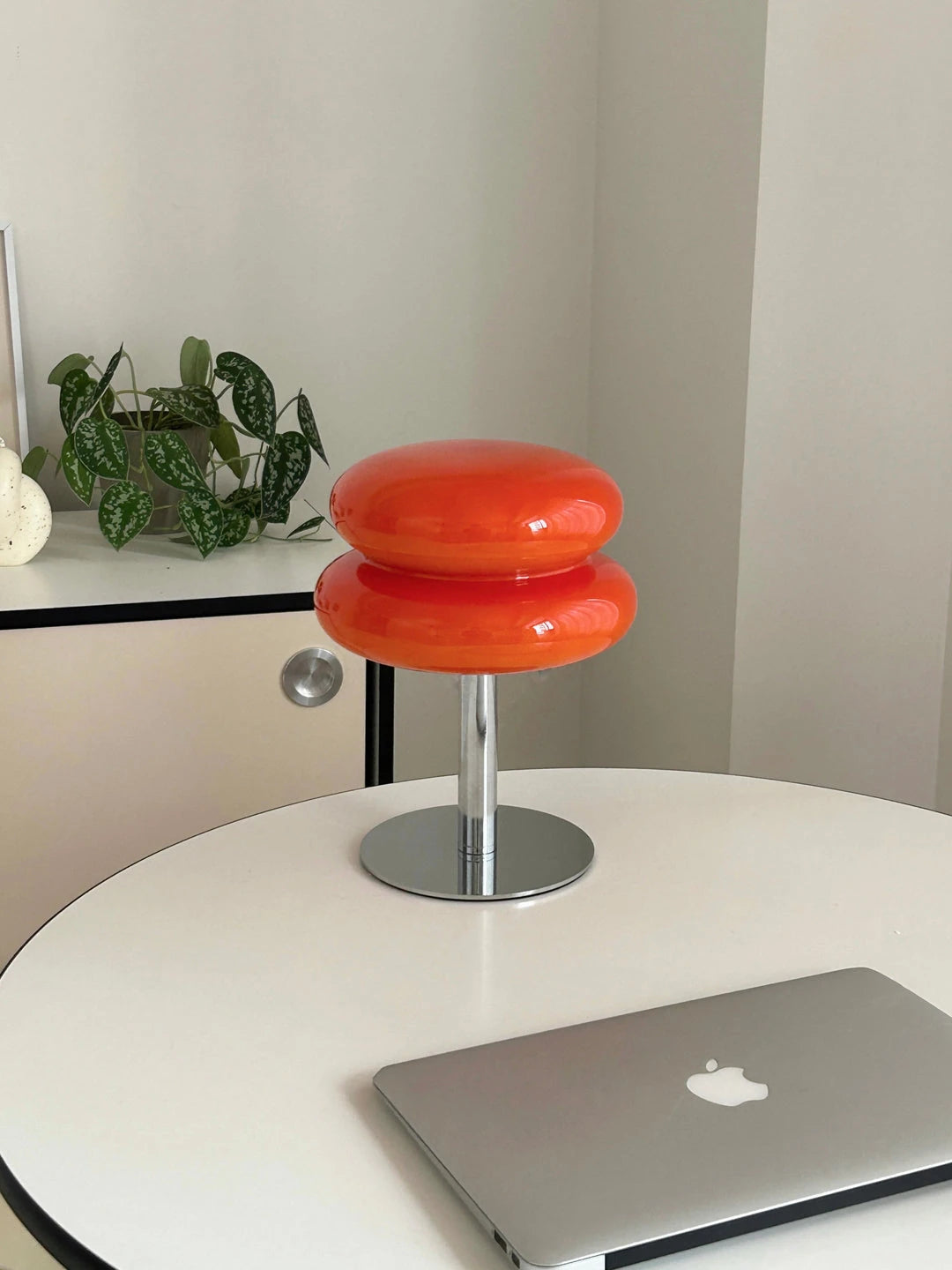 Lumi Cloud naranja en una mesa redonda, junto a un portátil y una planta