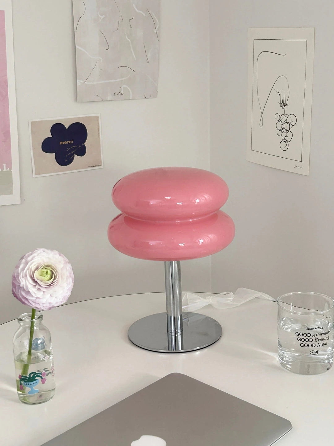 Lumi Cloud rosa en un escritorio, entre láminas, una flor y un portátil