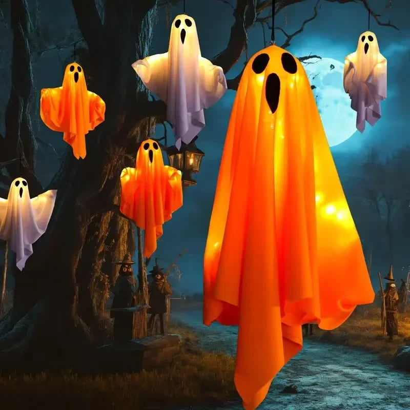 Fantasmas blancos y naranjas colgados de un árbol en una noche de Halloween