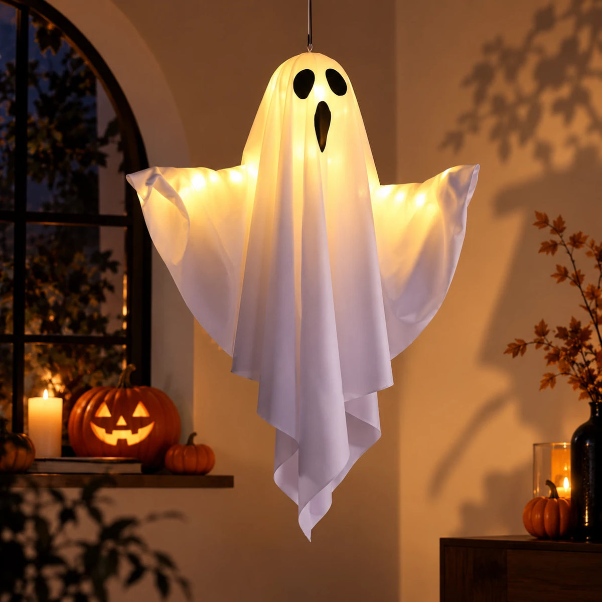 El Ghost Lights encendido colgado del techo de un salón, junto a una ventana con calabazas