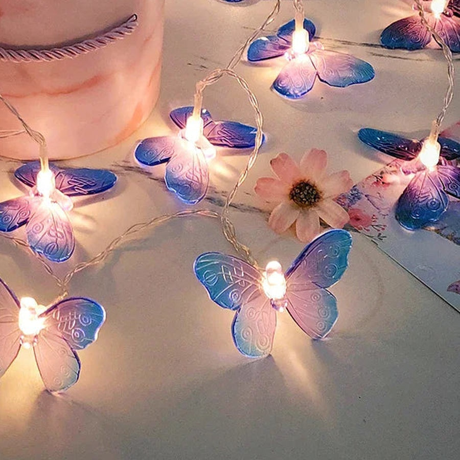 Guirnalda de mariposas moradas encendida sobre una mesa de mármol rosa