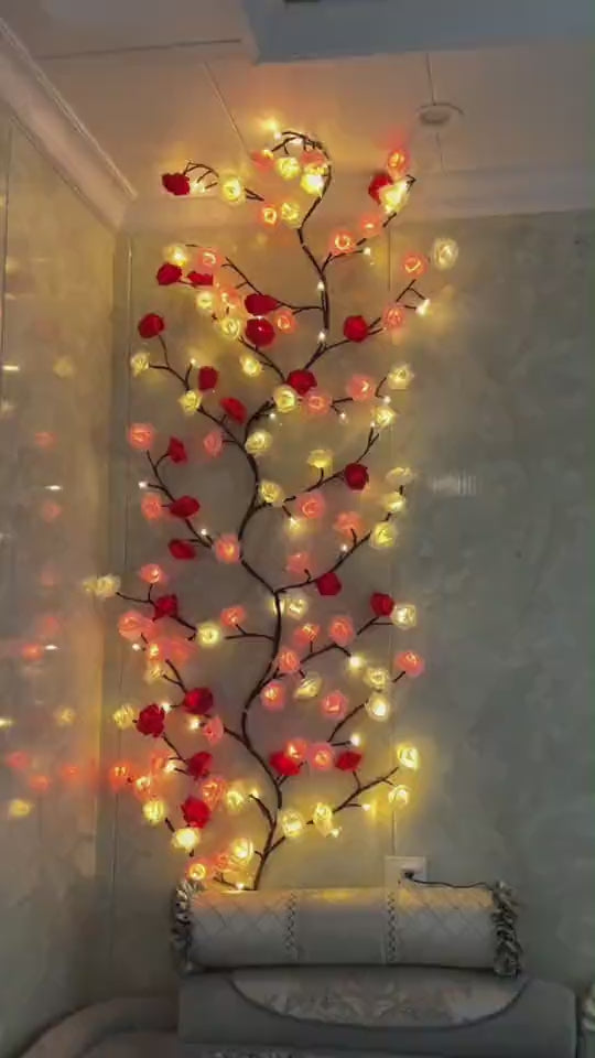 Amore Lights encendida en una pared: la enredadera de rosas rojas, crema y empolvadas con la luz cálida dentro de cada flor