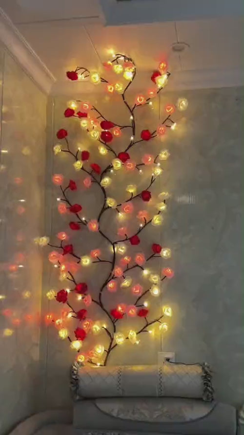 Amore Lights encendida en una pared: la enredadera de rosas rojas, crema y empolvadas con la luz cálida dentro de cada flor