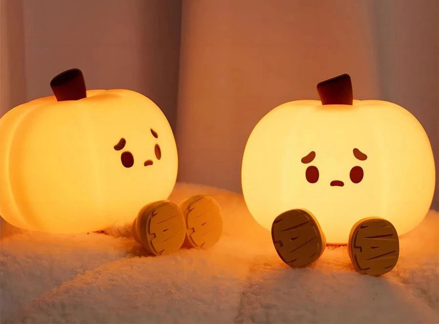 Dos Pumpkin Lume encendidas sobre una manta, con sus piernecitas de madera