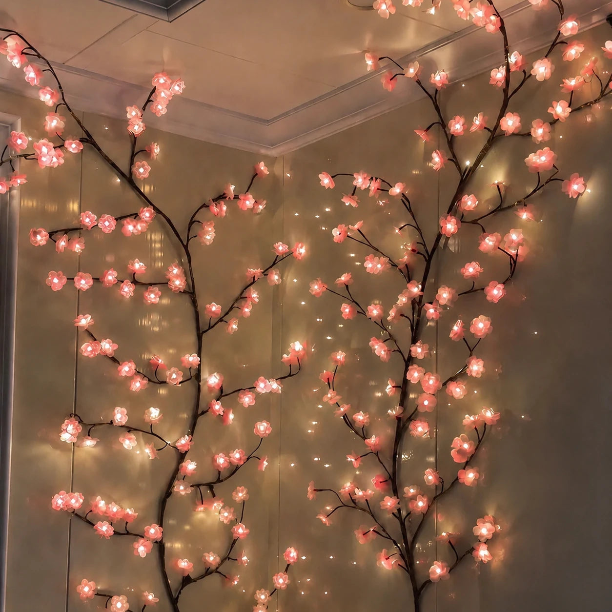Guirnalda Sakura encendida en la esquina de una habitación, con las dos ramas subiendo hasta el techo